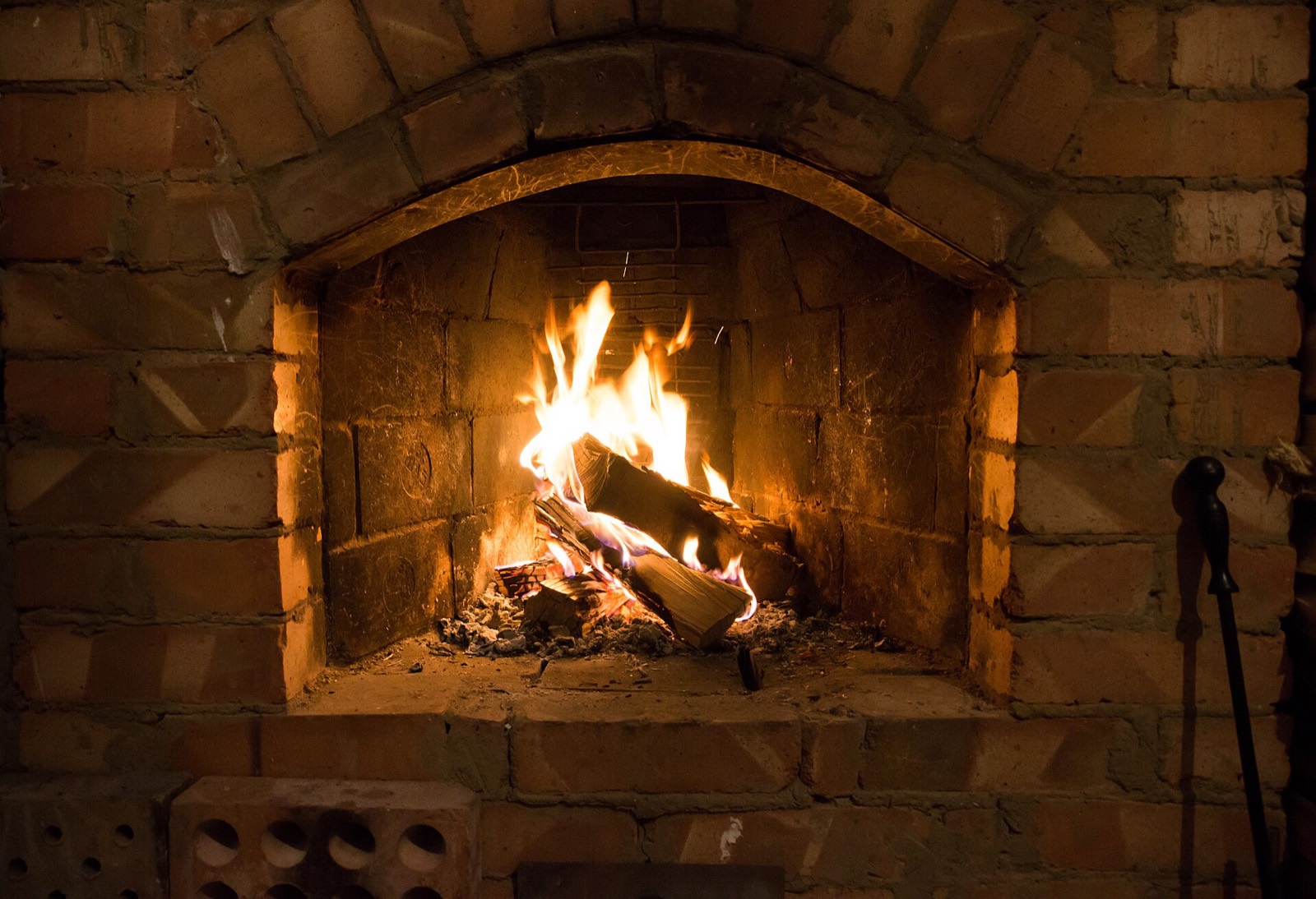 A wood fire burning inside an arched brick hearth